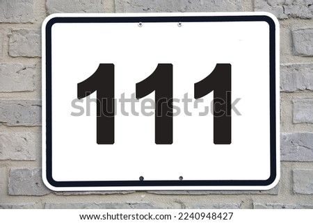 A white house number plaque, on a grey brickwall, showing the number one hundred eleven (111)