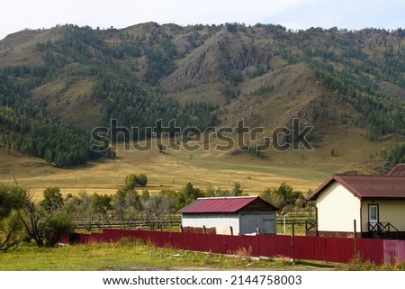 White houses with the red roofs on a background of high mountain in the village of Gorny Altai, Siberia, Russia. Natural landscape
