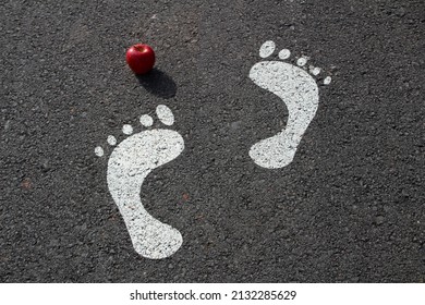 White Human Footprints And Red Apple. Adam And Eve And The Forbidden Apple. 