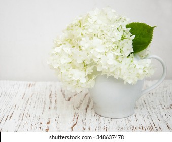 White Hydrangea In A White Vase On A Wooden Background