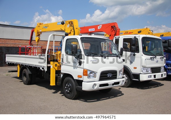 White Hyundai\
flatbed trucks with yellow, red crane arm is in the parking lot -\
Russia, Moscow, 30 August\
2016