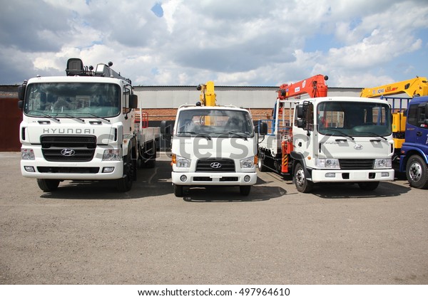 White\
Hyundai flatbed trucks with yellow, red, black crane arm is in the\
parking lot - Russia, Moscow, 30 August\
2016