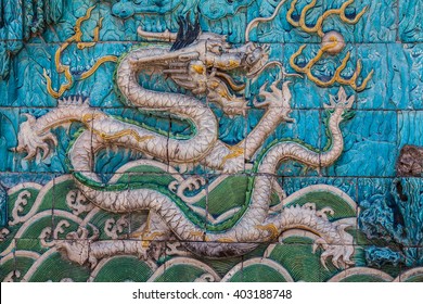 White imperial dragon with green crest and long curved tail on the famous nine dragon wall in the Forbidden City in Beijing - Shutterstock ID 403188748