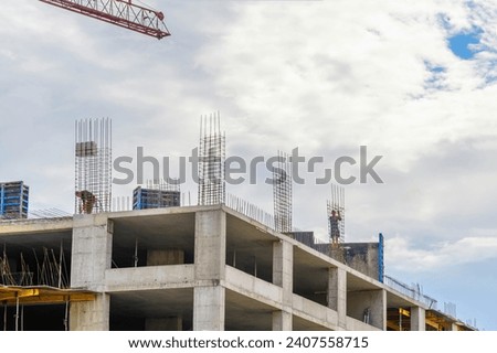 It is  white incomplete brick building. It is the unfinished European apartment building. it is blue sky with white cloud in midday.