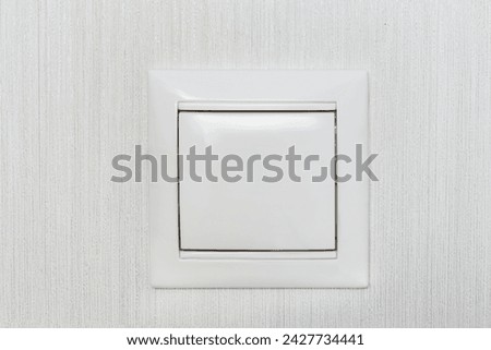 White indoors light switch on a white wallpaper wall closeup as a background
