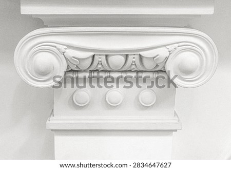 White ionic column capital featuring a classical volute and sculpted decorative elements