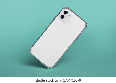 White IPhone 11 In Clear Silicone Case Falls Down Isolated On Green Background Back View. IPhone 12 Case Mockup