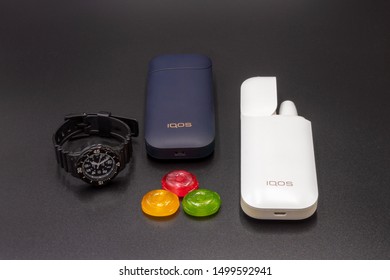 White Iqos Device Battery, Multicolored Sweet Candy, Black Teen Wristwatch And Black Iqos Device Battery. Iqos Electronic Cigarette Ban Concept In The USA.  September 08, 2019. 