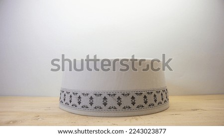 White Islamic caps with black patterns are usually worn by Muslim men with a wooden background