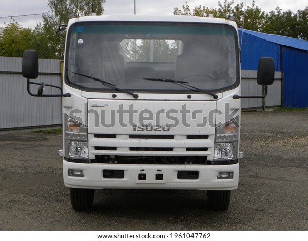 A white Isuzu flatbed truck with a large body stands\
in a working parking lot on autumn Street-Russia, Moscow, October\
30, 2020
