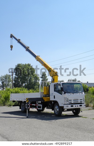 A White Isuzu\
flatbed truck with yellow crane arm is in the parking lot - Russia,\
Moscow, 30 August 2016
