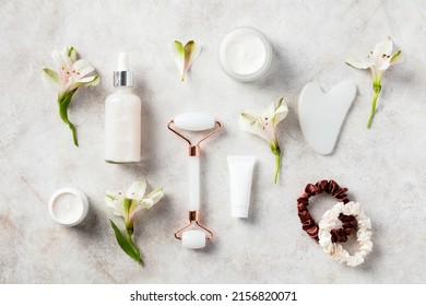 White Jade Face Roller, Gua Sha, Serum, Moisturizer, Cream On Stone Table. Natural Beauty Products Set. Flat Lay, Top View. 