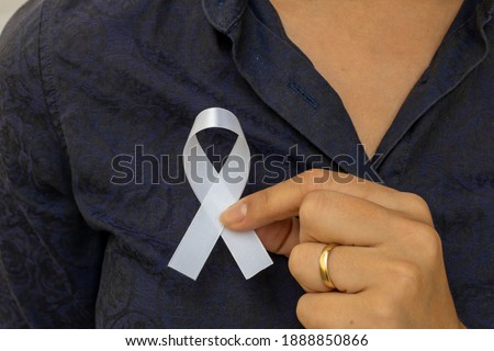 White January, mental health awareness campaign. woman putting white ribbon on her shirt. 