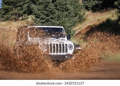 A white Jeep drives through water on a 4x4 trail in Colorado.