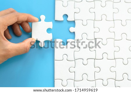 White jigsaw in the hands, The correct solution. Teamwork, Solving and completing the task. Last piece of jigsaw puzzle. Assembling  jigsaw puzzle pieces.
