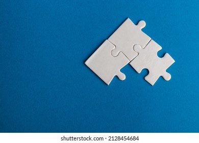 White jigsaw puzzle pieces on blue background. Texture photo with space for text. Teamwork conceptual photo.