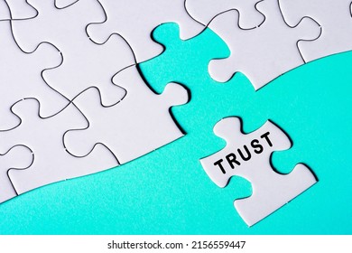 White jigsaw puzzle with word trust over blue background. Relationship and business concept.