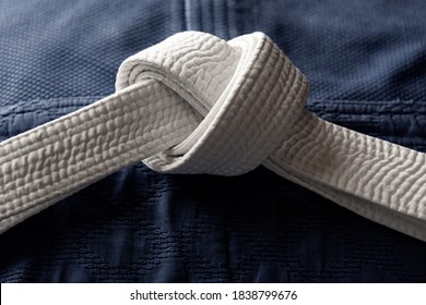 White judo, aikido or karate belt on blue budo gi. Concept is applicable to sports, business or education