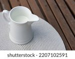White jug with milk on a wooden table. Breakfast on the veranda. Fresh drink, autumn leaves and oudoor. Close up photography