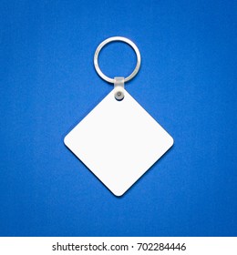 White Key Ring On Blue Background. Key Chain For Your Design. Hanging Accessory Or Souvenir. ( Square Shape )