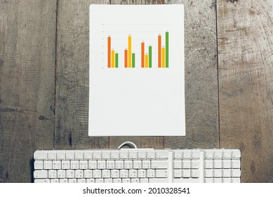 White Keyboard With Chart Data TOp View On Wooden Background , Working From Home Concept