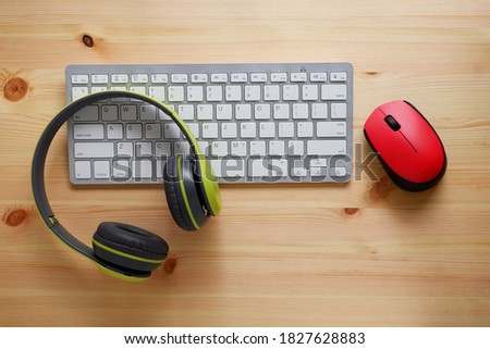 White keyboard with wireless mouse and bluetooth wireless headphones on wooden background.Top view. Computer equipment accessories