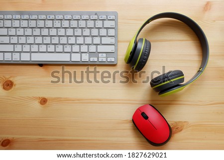 White keyboard with wireless mouse and bluetooth wireless headphones on wooden background.Top view. Computer equipment accessories