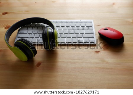 White keyboard with wireless mouse and bluetooth wireless headphones on wooden background.Top view. Computer equipment accessories