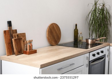 White kitchen counter with cutting boards, electric stove and condiments