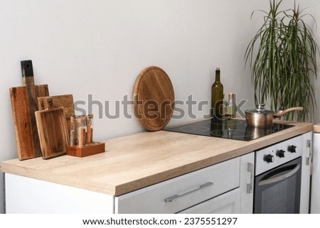 White kitchen counter with cutting boards, electric stove and condiments