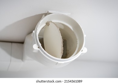 White kitchen exhaust pipe in the dust. Plastic air vent. Mechanical duct closing valve.