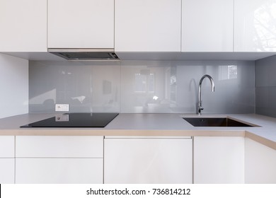 White Kitchen With Gray Backsplash, Sink And Induction Hob