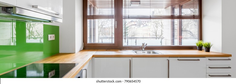 White Kitchen With Modern Cupboards, Green Backsplash And Window, Panorama