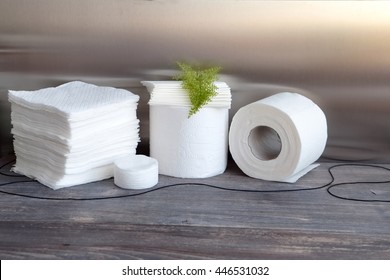White kitchen paper towel, toilet paper, paper tissues, cotton pads on a wooden table