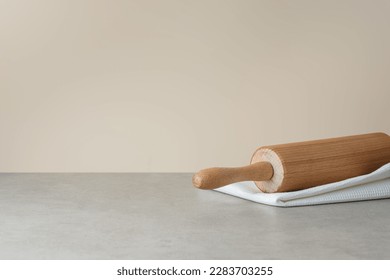 white kitchen towel and rolling pin on gray background, side view
