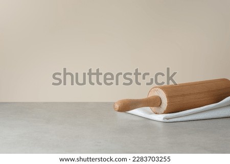 white kitchen towel and rolling pin on gray background, side view