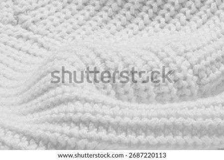 A white knit sweater with a pattern of white yarn. The sweater is knitted and has a soft texture