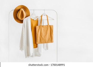 White Knitted Jumper On Hanger With Brown Hat And Eco Bag On White Background. Elegant  Fashion Outfit. Spring Wardrobe. Minimal Concept.