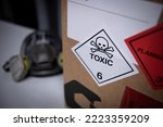 White label with toxic symbol on a box and a mask in the background.