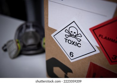 White label with toxic symbol on a box and a mask in the background.