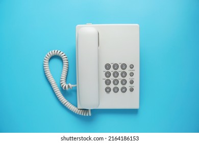 White Landline Telephone With Grey Buttons Isolated On Blue Or Pastel Background