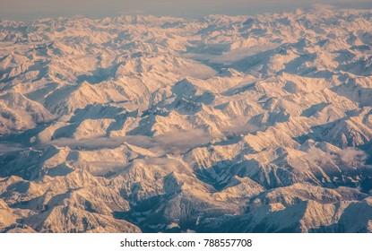 White Landscape from 40,000 feet up. High above British Columbia Mountain Peaks covered in Deep Magical Snow in the Pacific Coastal Mountain Range