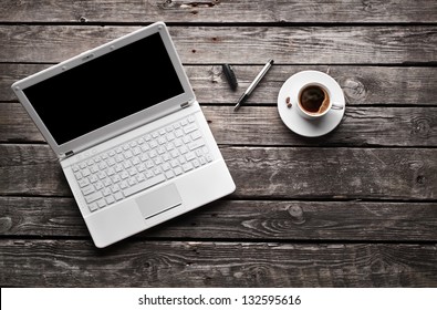 White laptop with coffee cup and pen on old wooden table. - Powered by Shutterstock