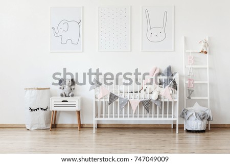 White laundry bag with painted eyelashes standing next to a nightstand with a stuffed animal elephant sitting on it in a children room interior