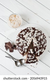 White Layered Almond Cake With Melted Chocolate On Top On A White Tablecloth With A China Set, Vintage Forks, Almond Flakes