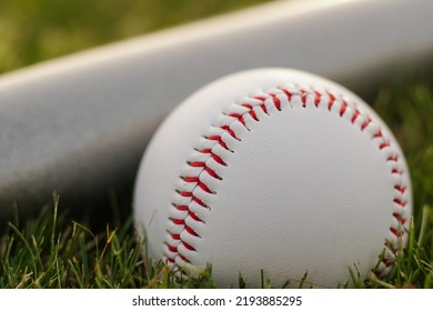 White Leather Ball And Baseball Bat On The Grass, Close Up