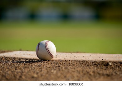 A white leather baseball lying on top of the pitcher's mound at a baseball field with copy space