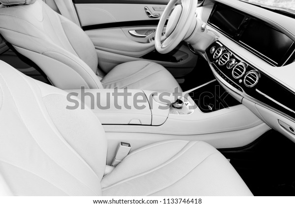 White leather interior of the luxury modern car.\
Leather white seats and multimedia. Steering wheel and dashboard.\
Automatic gear stick. Modern car interior details. Car detailing.\
Black and white
