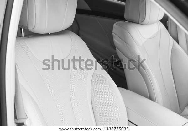 White leather interior of the luxury modern car.\
Leather comfortable white seats and multimedia. exclusive wood and\
metal decoration. Modern car interior details. Car detailing. Black\
and white