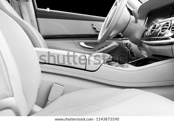White\
leather interior of the luxury modern car. Leather comfortable\
white seats and multimedia. Steering wheel and dashboard. Automatic\
gear shift. Car interior details. Black and\
white